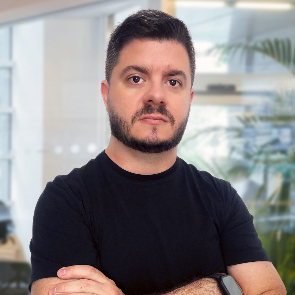 Headshot of Leandro, white man, short beard, dark colored eyes, black t-shirt, serious expression..